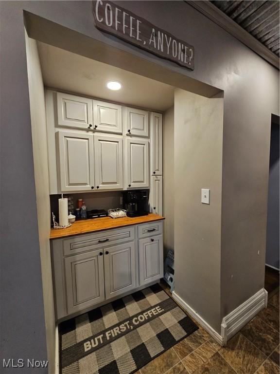 kitchen with recessed lighting, white cabinets, wood counters, and baseboards