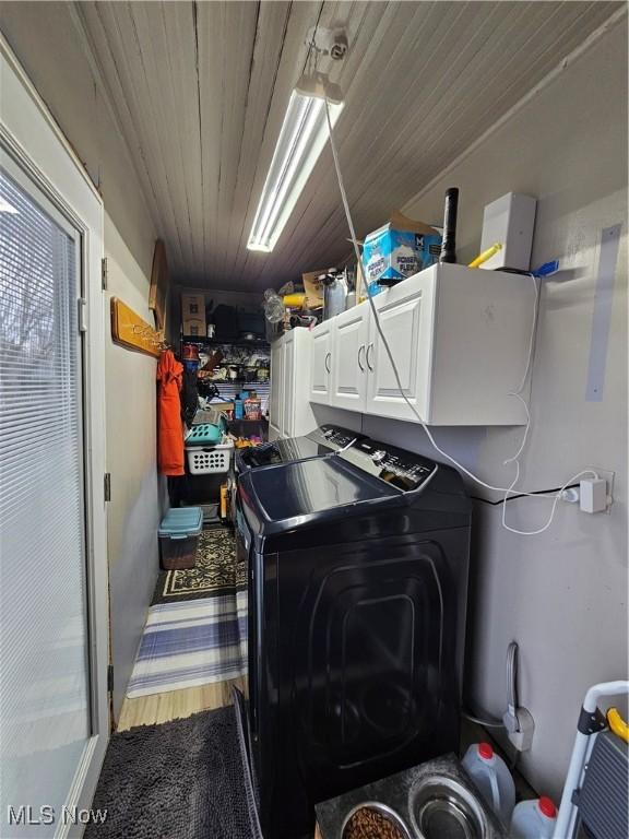 laundry area with wood ceiling, washer and clothes dryer, wood finished floors, and cabinet space