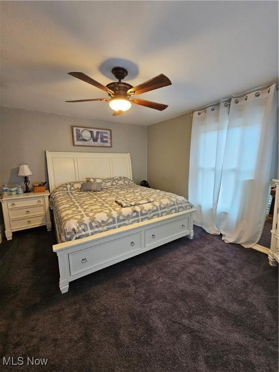 bedroom with a ceiling fan and dark colored carpet