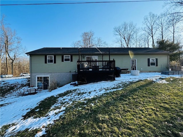 snow covered back of property featuring a yard, a wooden deck, and central AC unit