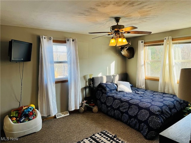 carpeted bedroom featuring ceiling fan and visible vents