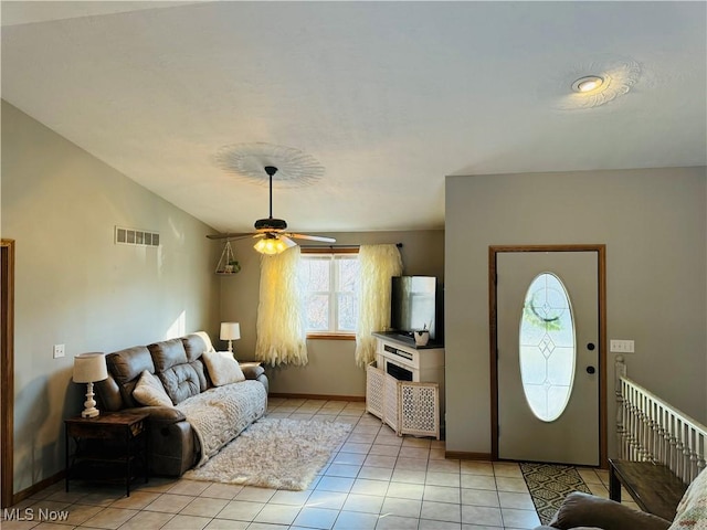 living room featuring visible vents, light tile patterned flooring, vaulted ceiling, ceiling fan, and baseboards