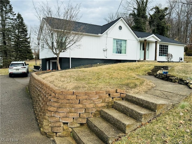 view of front of home featuring aphalt driveway, a front yard, and roof with shingles