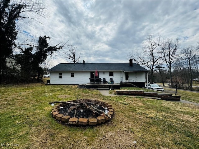 rear view of property with a fire pit and a yard