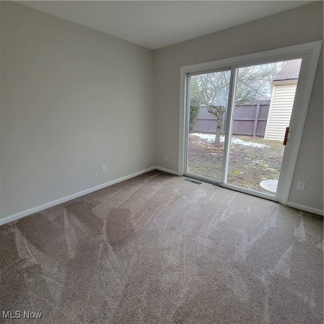 carpeted spare room with visible vents and baseboards