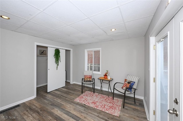 sitting room featuring a paneled ceiling, visible vents, baseboards, and dark wood-type flooring