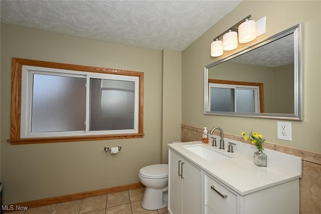 bathroom with tile patterned flooring, vanity, toilet, and a textured ceiling