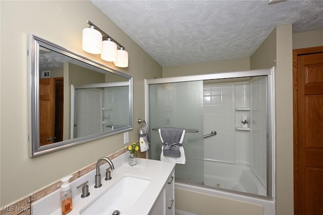 bathroom with a textured ceiling, combined bath / shower with glass door, and vanity