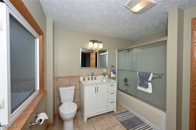 bathroom featuring bath / shower combo with glass door, toilet, tile patterned floors, a textured ceiling, and vanity