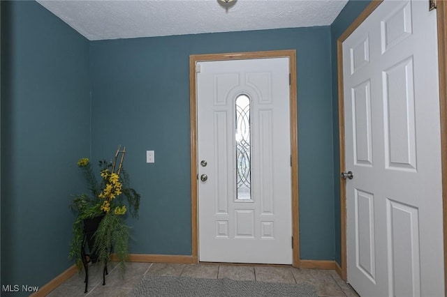 entryway with light tile patterned floors, baseboards, and a textured ceiling