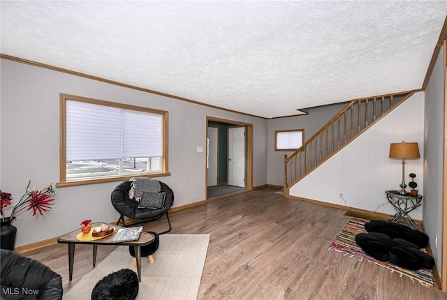 interior space featuring a textured ceiling, baseboards, stairway, light wood-type flooring, and crown molding