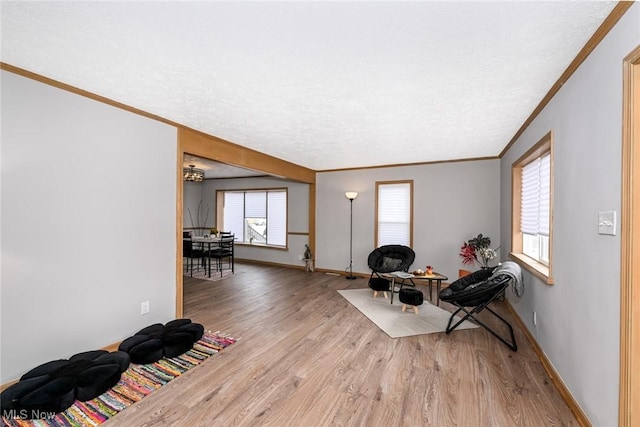 living area featuring baseboards, a textured ceiling, light wood-type flooring, and crown molding