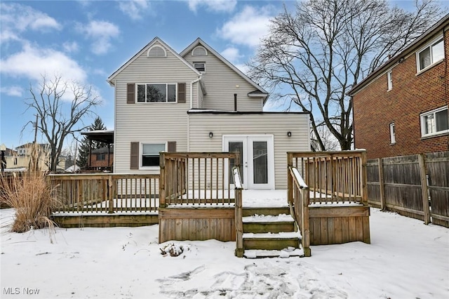 snow covered rear of property with fence and a deck