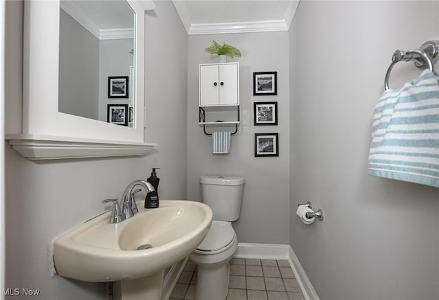 bathroom with crown molding, toilet, a sink, tile patterned flooring, and baseboards