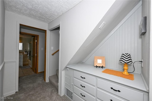 hallway featuring a textured ceiling and dark colored carpet