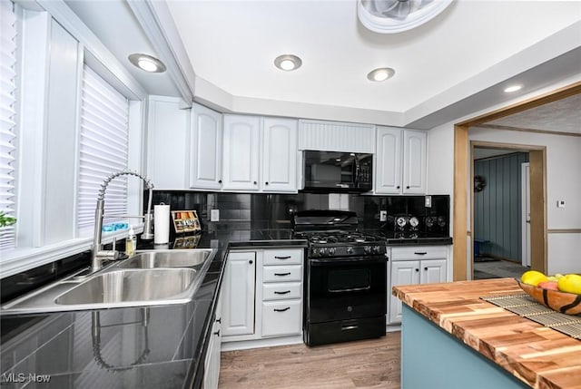 kitchen with black appliances, butcher block countertops, white cabinets, and a sink