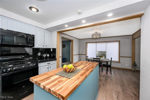 kitchen with white cabinetry, wooden counters, light wood-type flooring, a center island, and black appliances