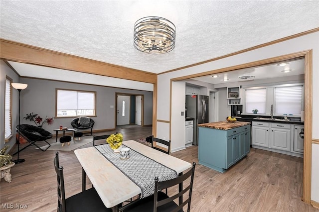 dining space with light wood-style floors, crown molding, and a textured ceiling