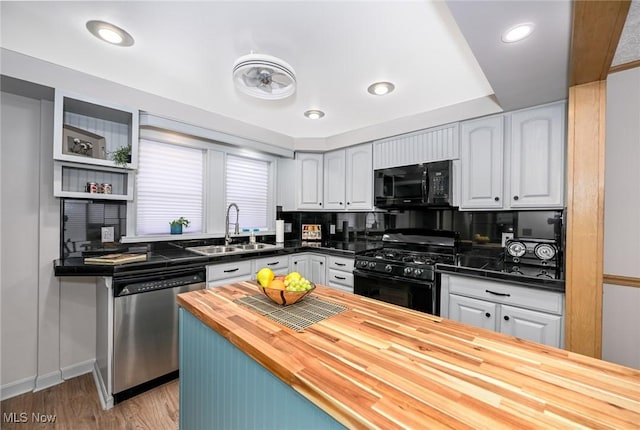 kitchen featuring light wood-style floors, a sink, black appliances, open shelves, and wooden counters