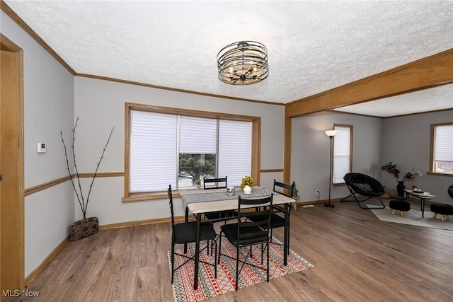 dining space featuring a textured ceiling, wood finished floors, and baseboards