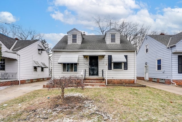 new england style home with a shingled roof and a front lawn