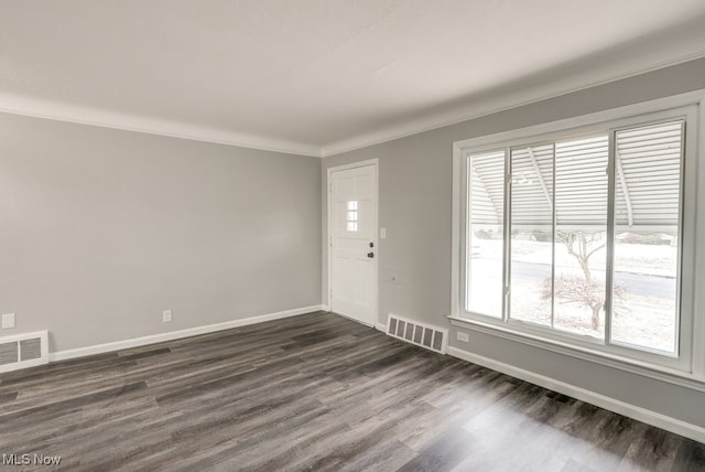 interior space featuring baseboards, visible vents, dark wood finished floors, and ornamental molding