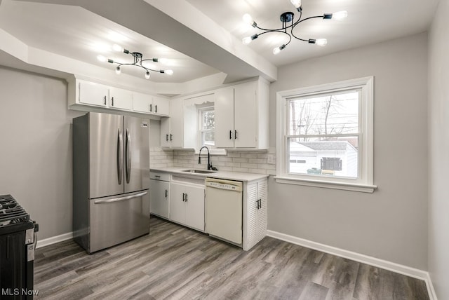 kitchen with white dishwasher, a sink, white cabinets, light countertops, and freestanding refrigerator