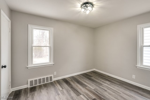 spare room featuring baseboards, visible vents, and dark wood finished floors