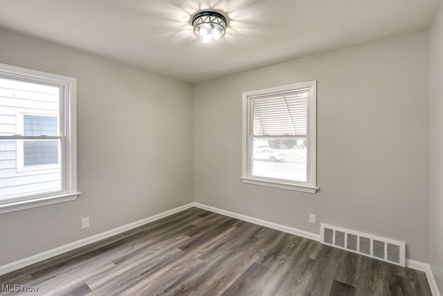 spare room featuring dark wood-style floors, visible vents, and baseboards