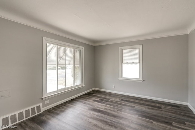 unfurnished room with a healthy amount of sunlight, visible vents, dark wood finished floors, and baseboards