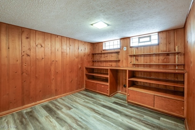 interior space with light wood-style floors, a textured ceiling, and wood walls