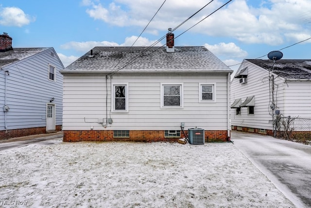 back of property featuring cooling unit, roof with shingles, and a chimney