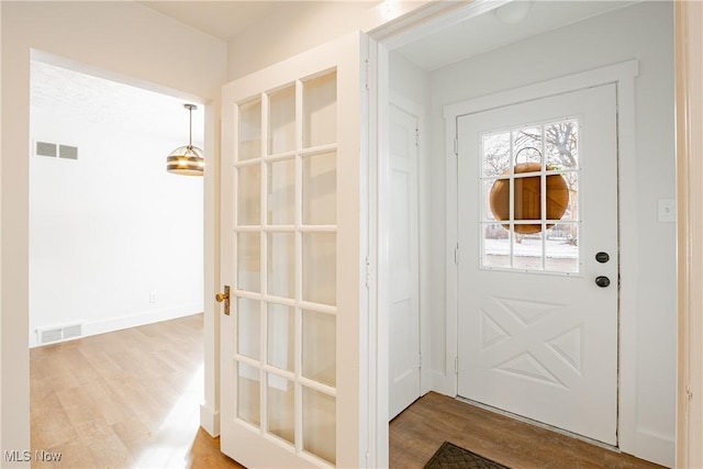 doorway featuring visible vents, baseboards, and wood finished floors