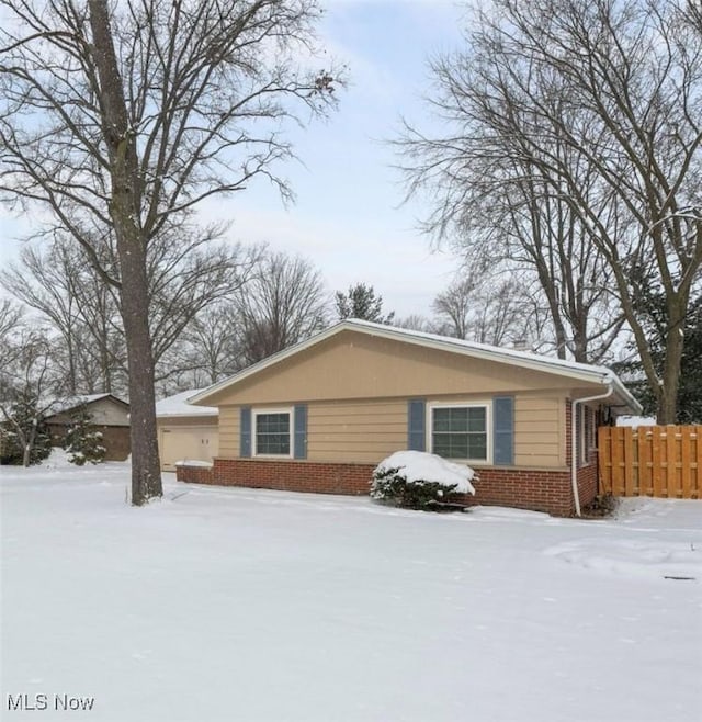 view of front of property featuring a garage, brick siding, and fence