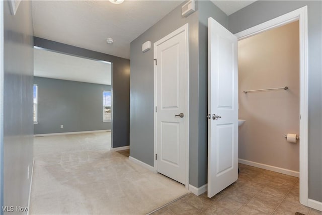 corridor featuring light carpet and baseboards