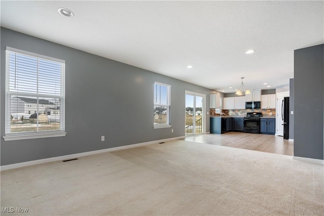 unfurnished living room featuring light carpet, visible vents, baseboards, and recessed lighting