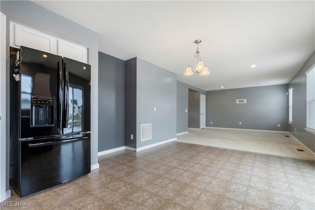 kitchen with baseboards, visible vents, open floor plan, white cabinetry, and black fridge