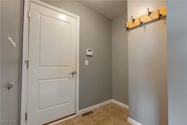 entryway with baseboards, visible vents, and a textured ceiling