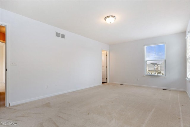 spare room featuring light carpet, visible vents, and baseboards