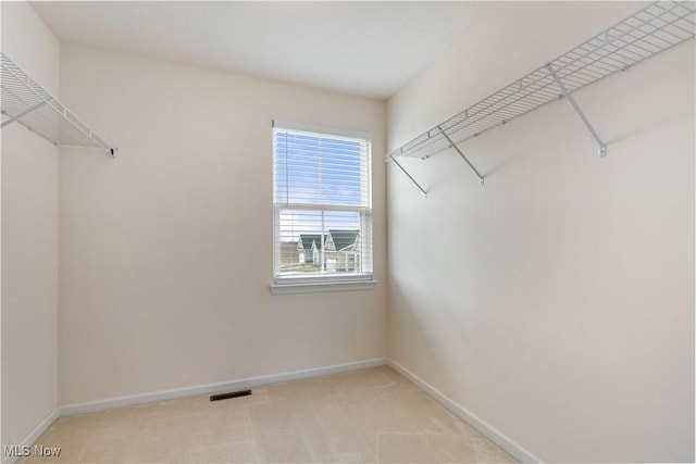 walk in closet with visible vents and light colored carpet