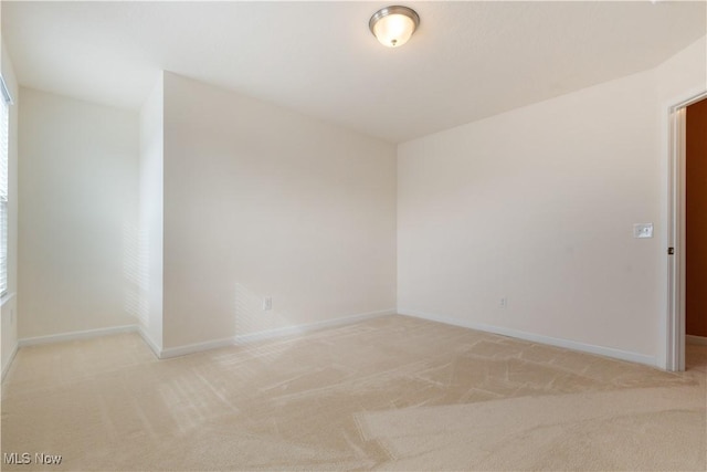 unfurnished room featuring light carpet and baseboards