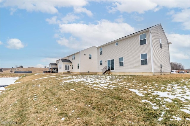 rear view of property featuring entry steps and a yard