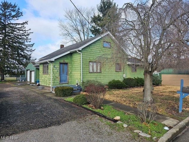 view of front of house with an attached garage, a chimney, and aphalt driveway