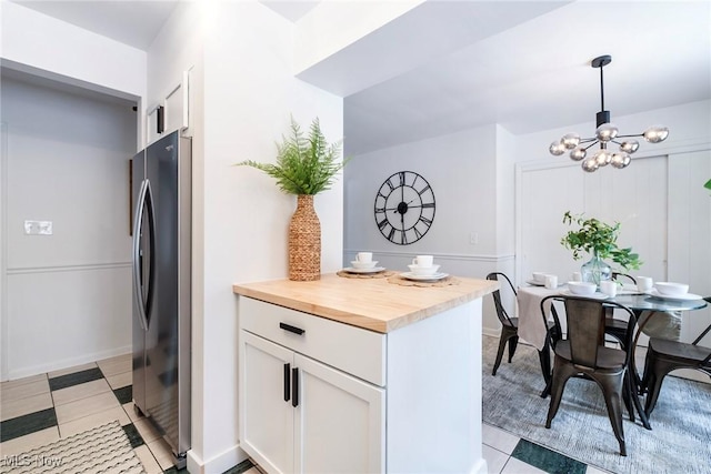 kitchen with a notable chandelier, wood counters, white cabinetry, freestanding refrigerator, and pendant lighting