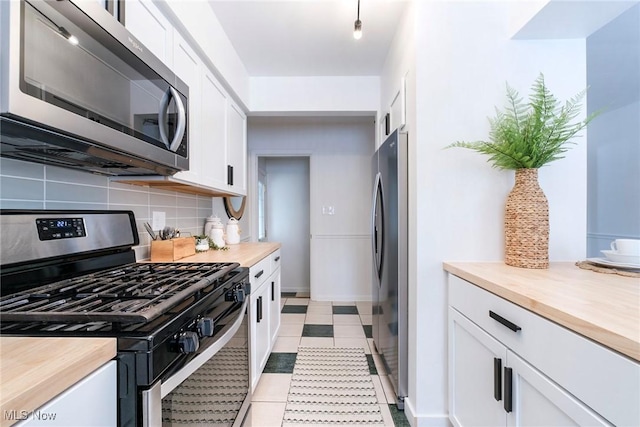 kitchen with stainless steel appliances, butcher block counters, white cabinets, and decorative backsplash