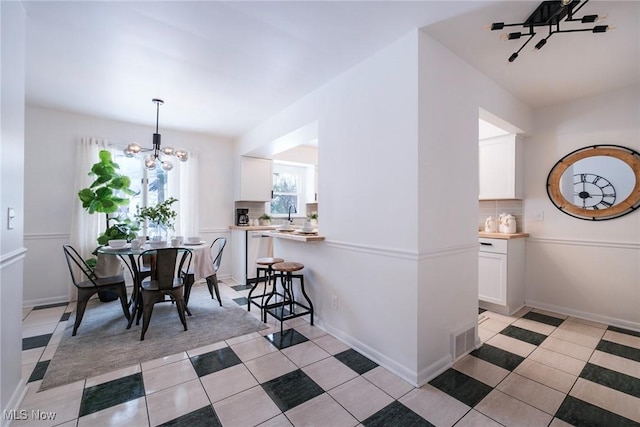 dining space featuring light tile patterned floors, baseboards, visible vents, and a chandelier