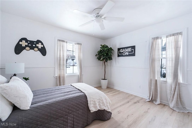 bedroom with light wood finished floors, baseboards, and a ceiling fan