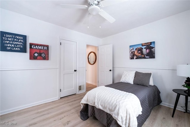 bedroom with light wood-type flooring, ceiling fan, visible vents, and baseboards