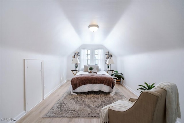 bedroom featuring lofted ceiling, light wood finished floors, and baseboards