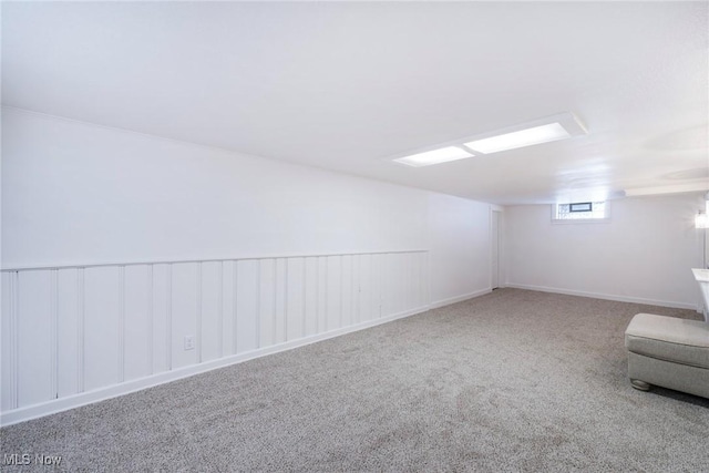 additional living space featuring carpet flooring and wainscoting